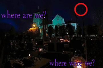 A photo of the outside of a building, which is lit up in cyan, at night. There are structures in front of it, which might be gravestones, but it's hard to tell. Sparkling text across the image reads 'where are we? where were we?'. A red circle can be seen in the top-right corner, seemingly drawing our attention to something, but what?